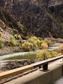 A flowing river hugs the curve of the highway in the Rockies.